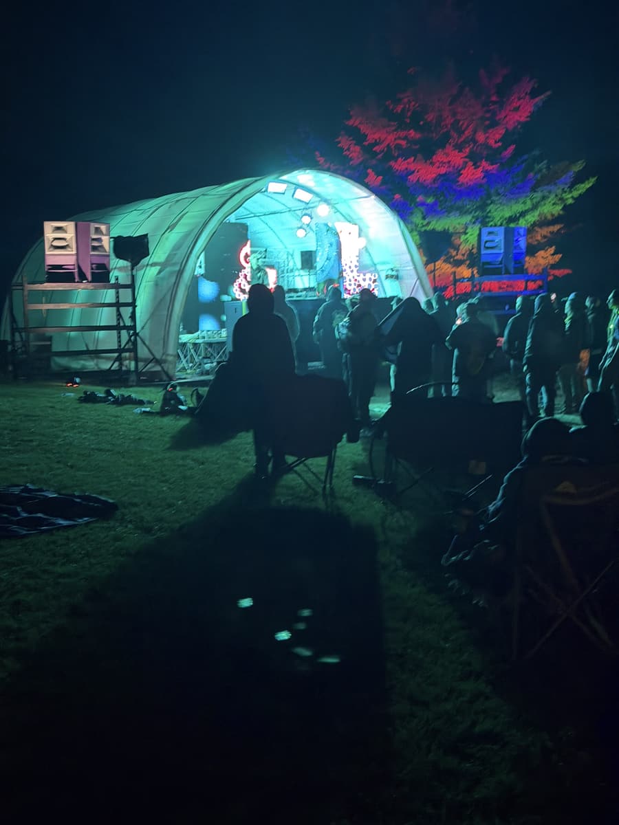 Dome stage at dusk with a lit tree, Funktion-One stack in the foreground