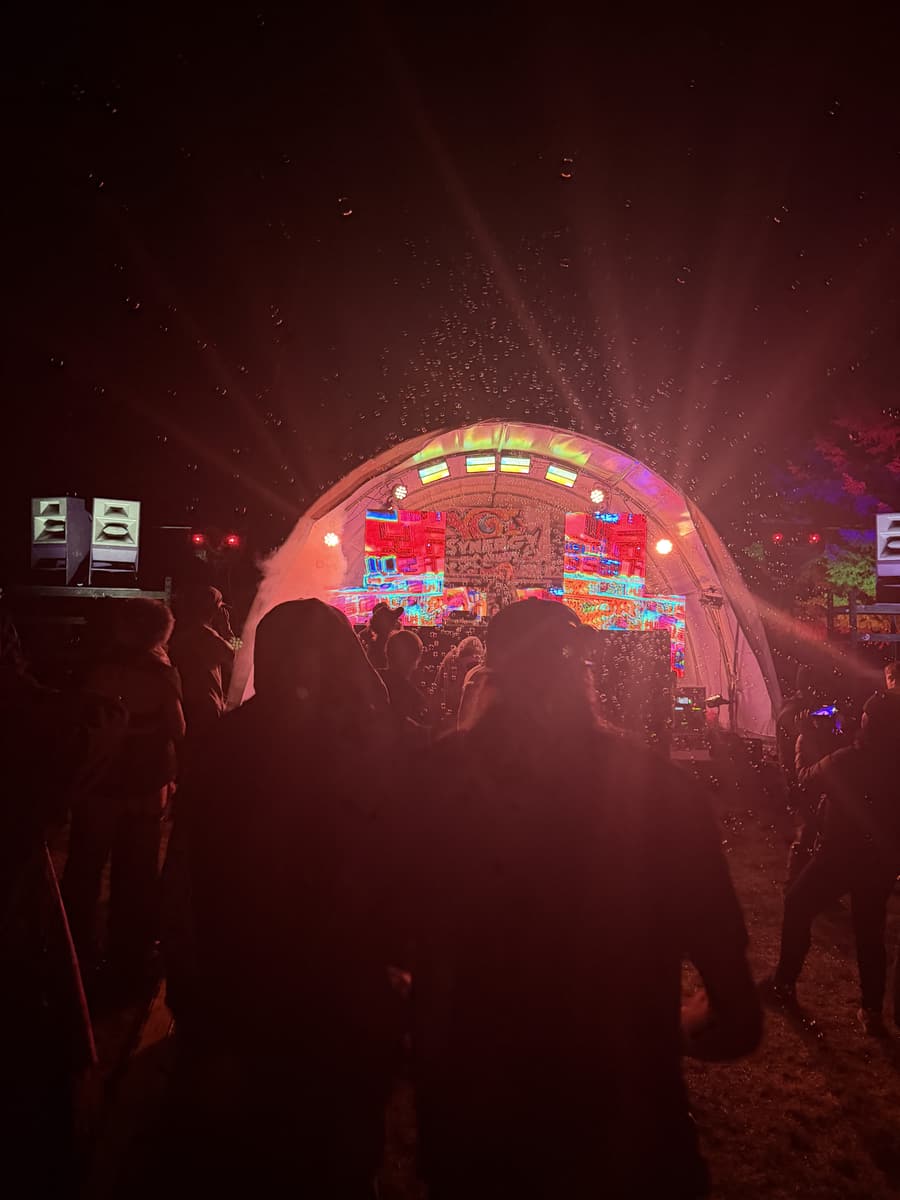 Dome stage washed in red light, crowd in front