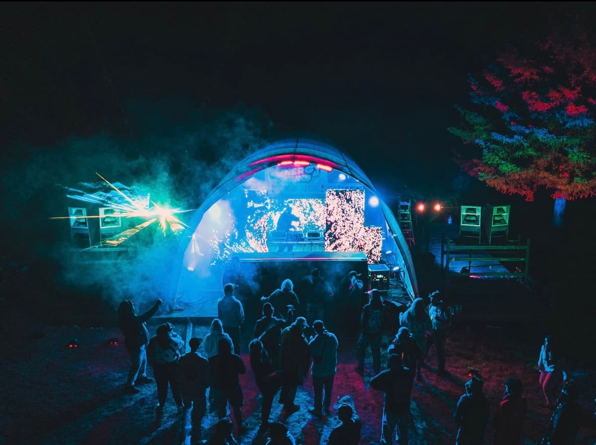 Dome stage at night with lasers, seen from behind the crowd